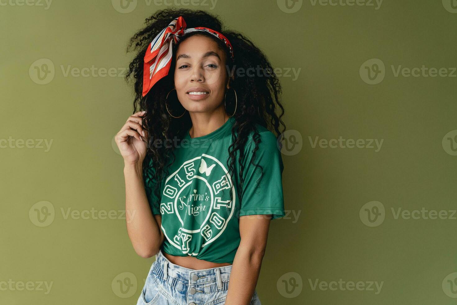 attractive black african american woman posing in stylish hipster outfit on green background photo