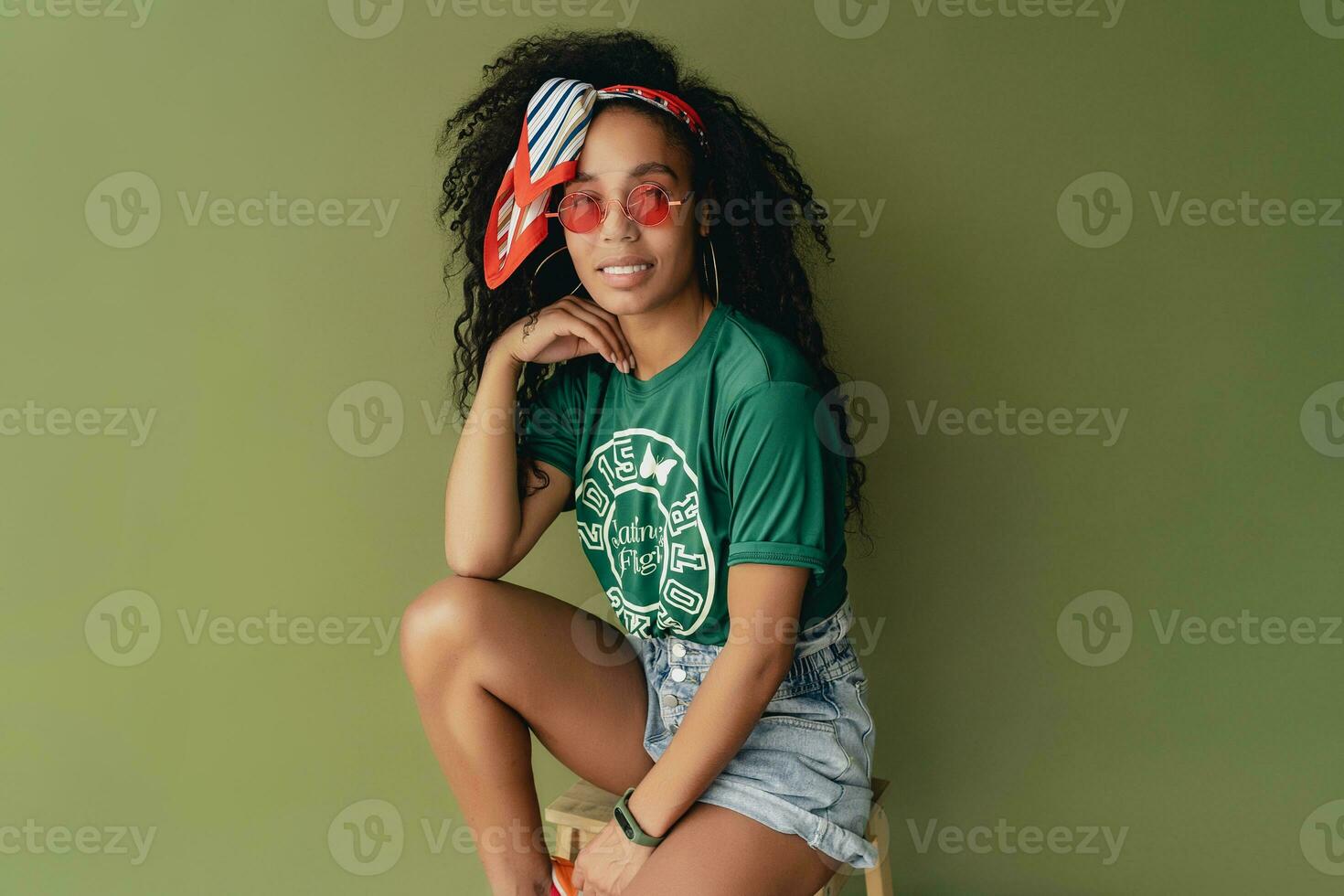 attractive black african american woman posing in stylish hipster outfit on green background photo