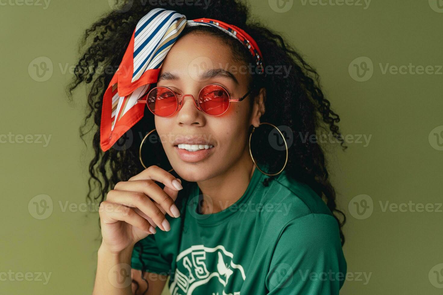 attractive black african american woman posing in stylish hipster outfit on green background photo