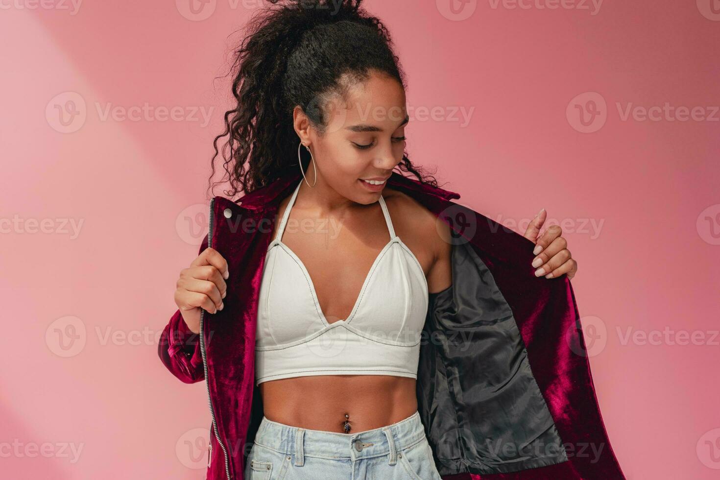 attractive black african american woman in stylish outfit on pink background photo
