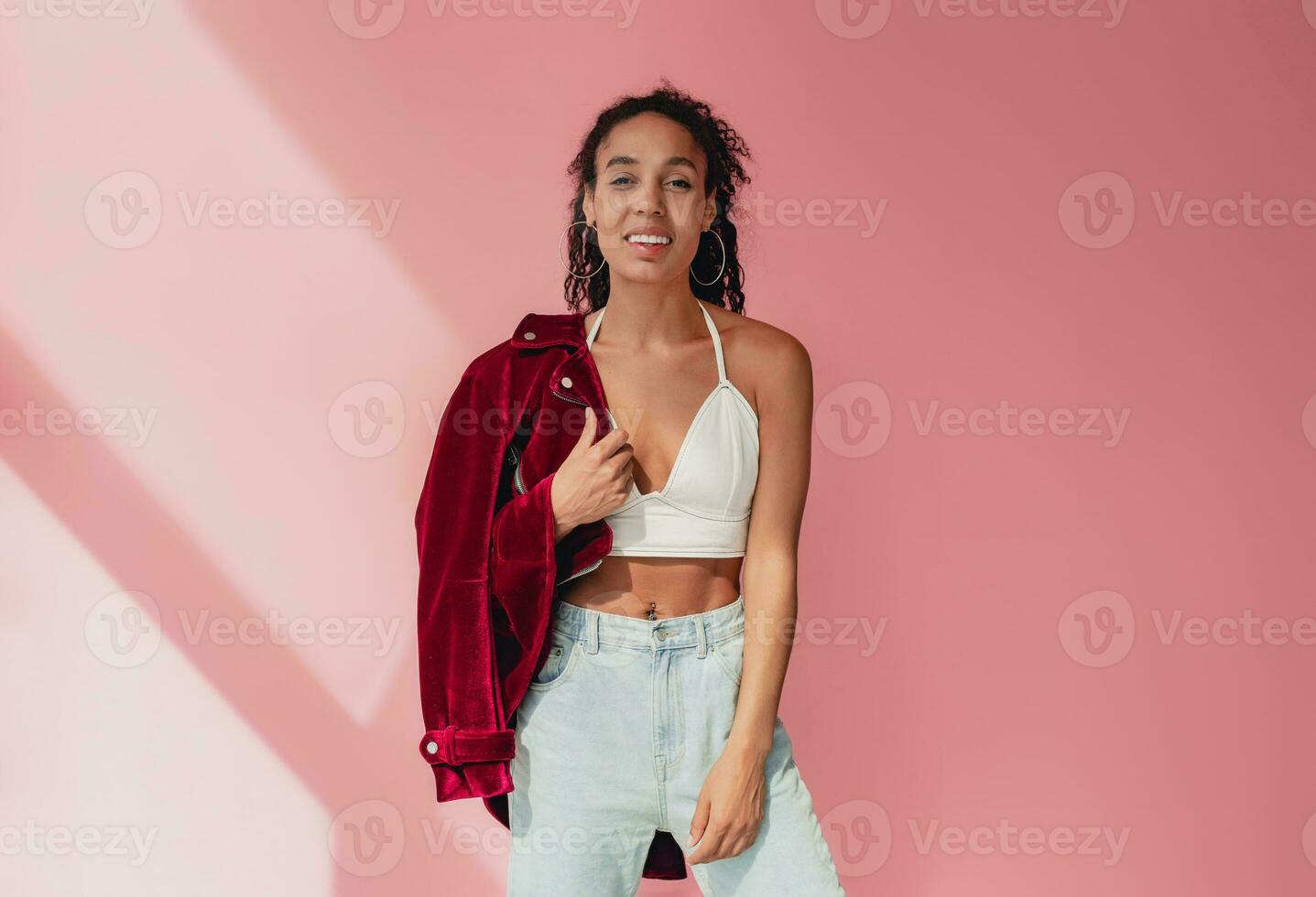 attractive black african american woman in stylish outfit on pink background photo