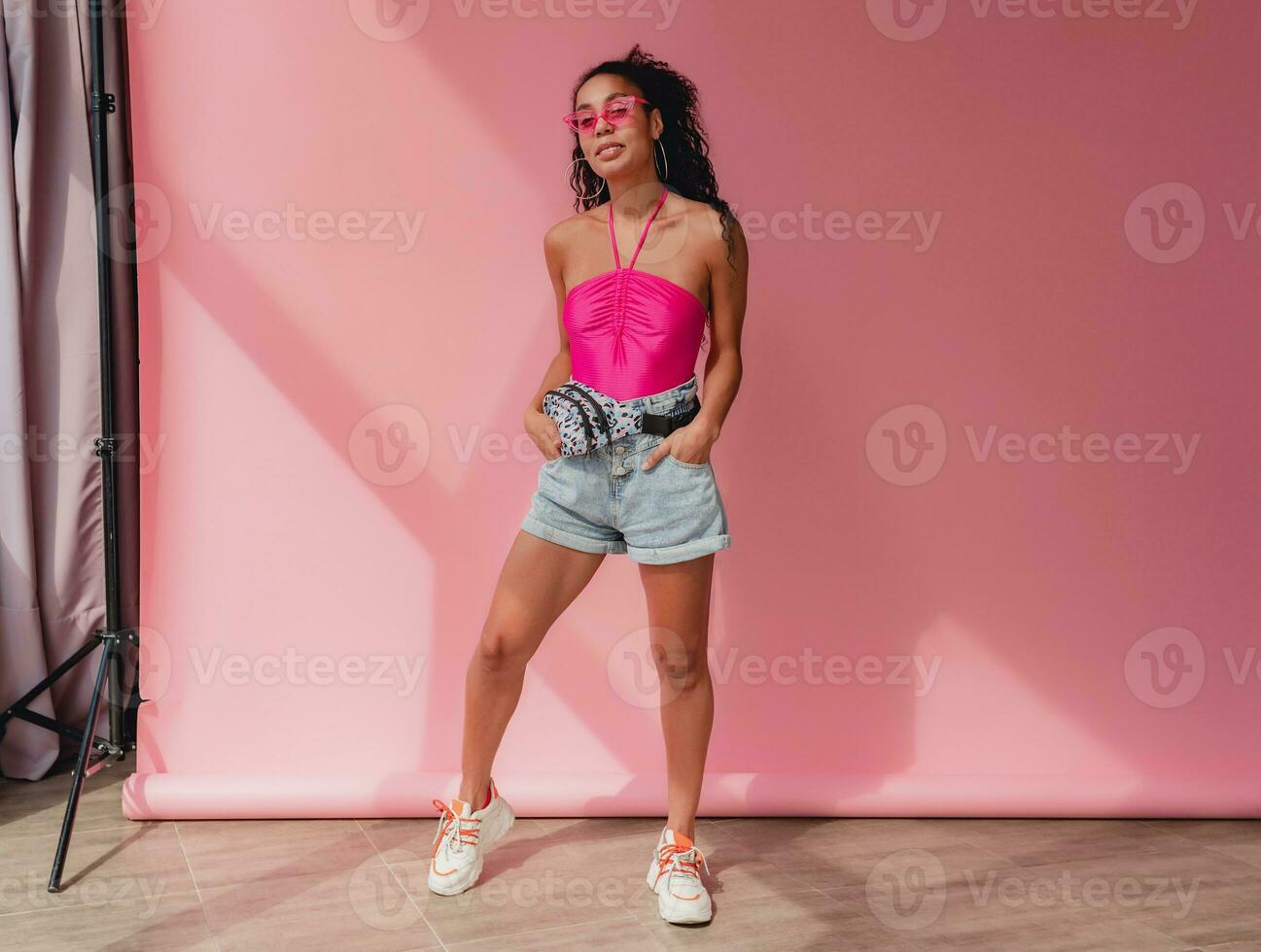 attractive black african american woman in stylish outfit on pink background photo