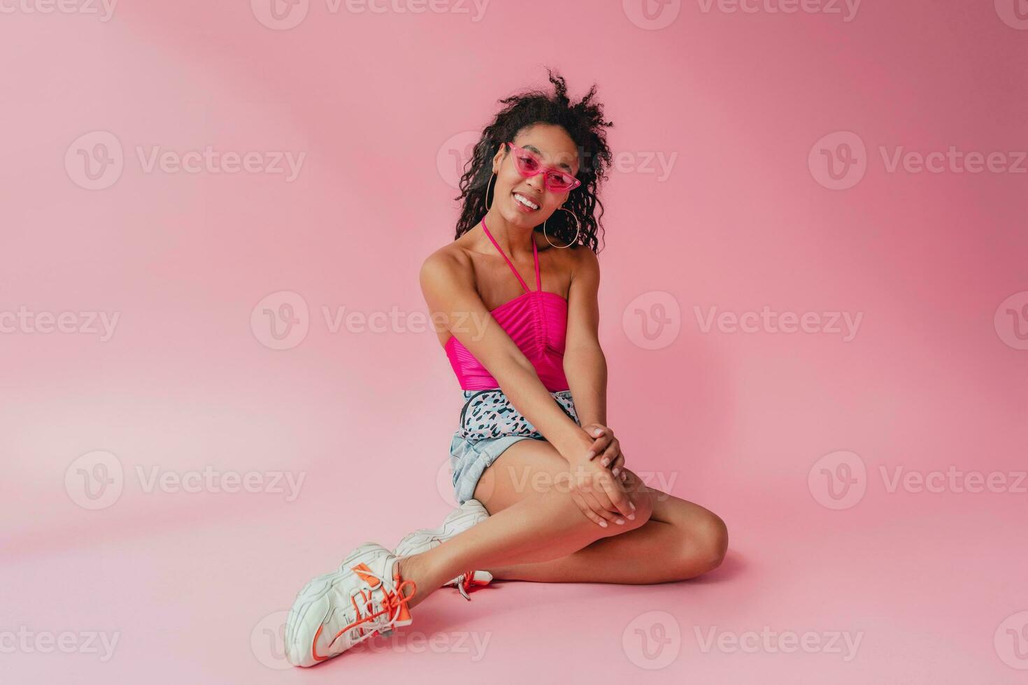 attractive black african american woman in stylish outfit on pink background photo