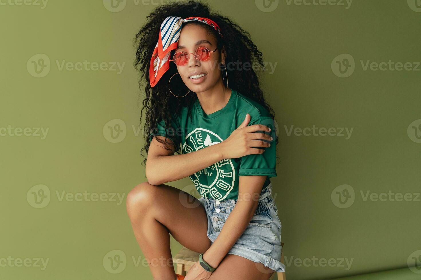 attractive black african american woman posing in stylish hipster outfit on green background photo