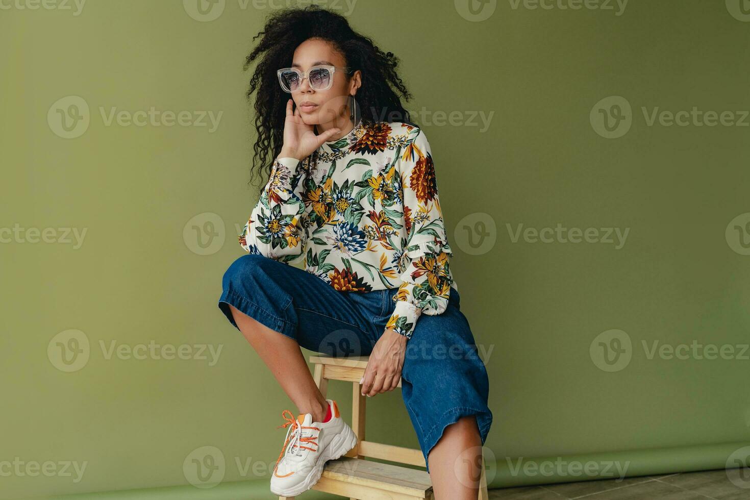 attractive black african american woman in stylish outfit on green studio background photo