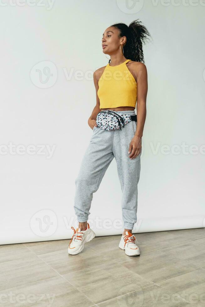 attractive black african american woman posing in stylish hipster outfit on white background photo