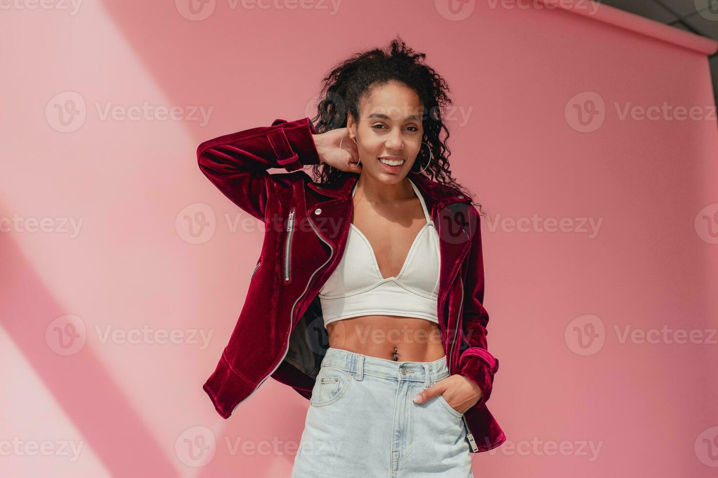 attractive black african american woman in stylish outfit on pink background photo