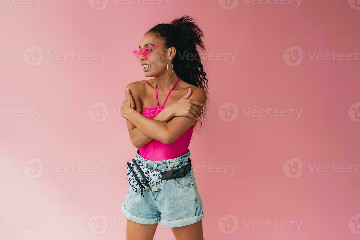 attractive black african american woman in stylish outfit on pink background photo