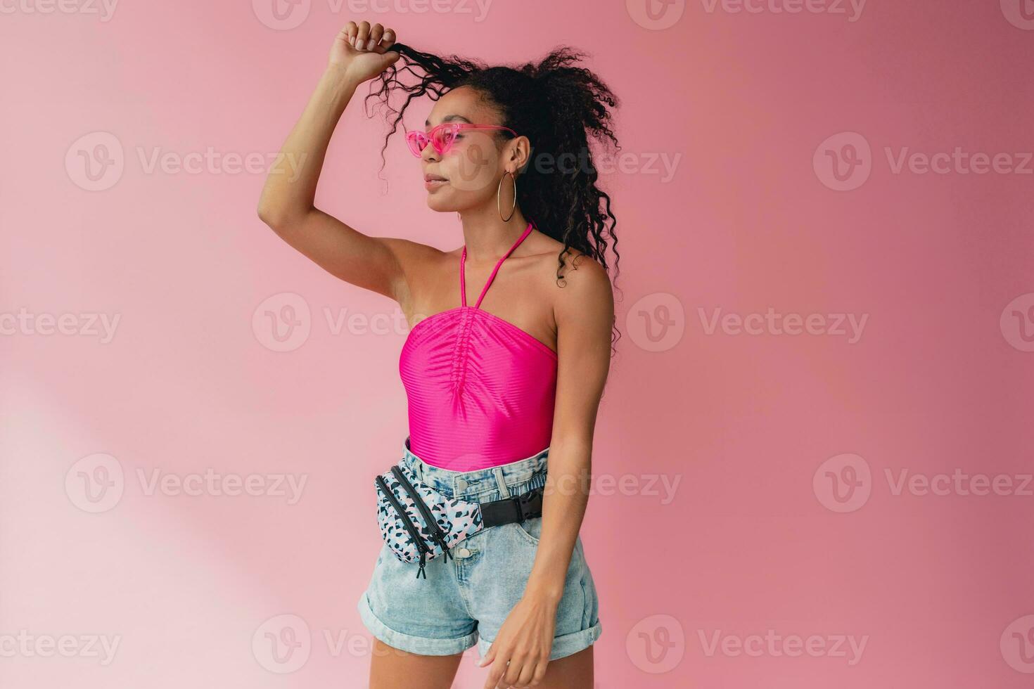 attractive black african american woman in stylish outfit on pink background photo