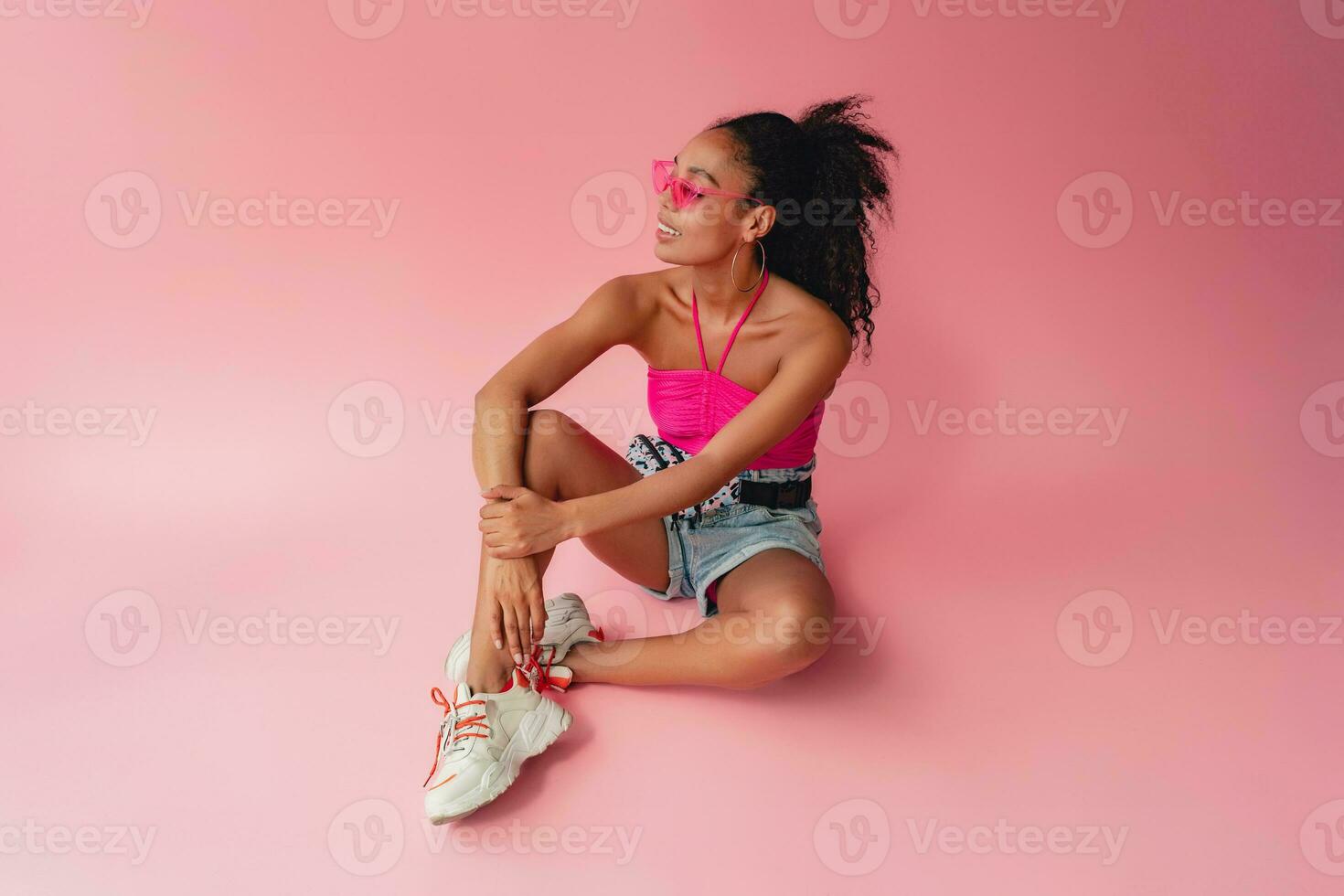 attractive black african american woman in stylish outfit on pink background photo