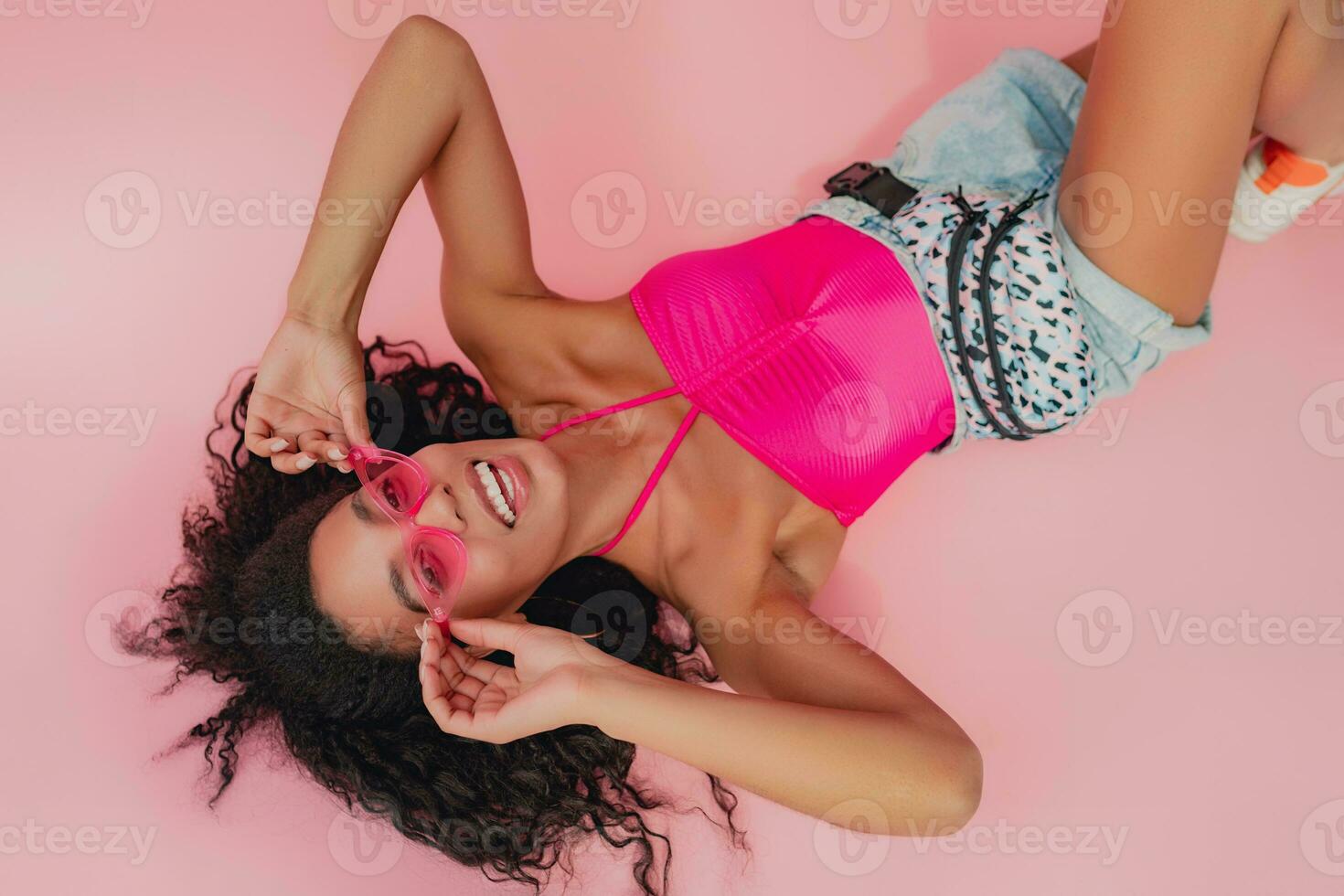 attractive black african american woman in stylish outfit on pink background photo