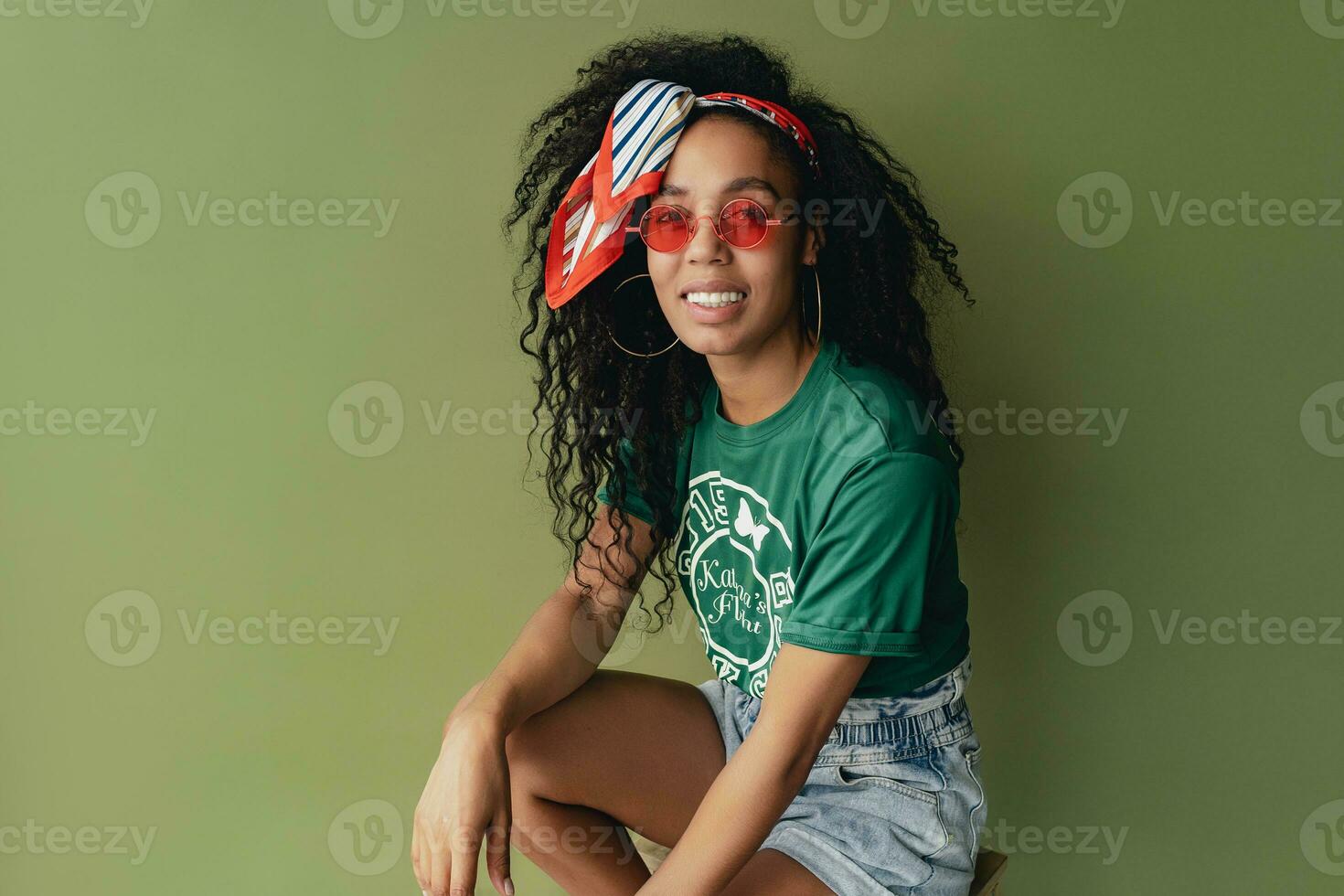 attractive black african american woman posing in stylish hipster outfit on green background photo