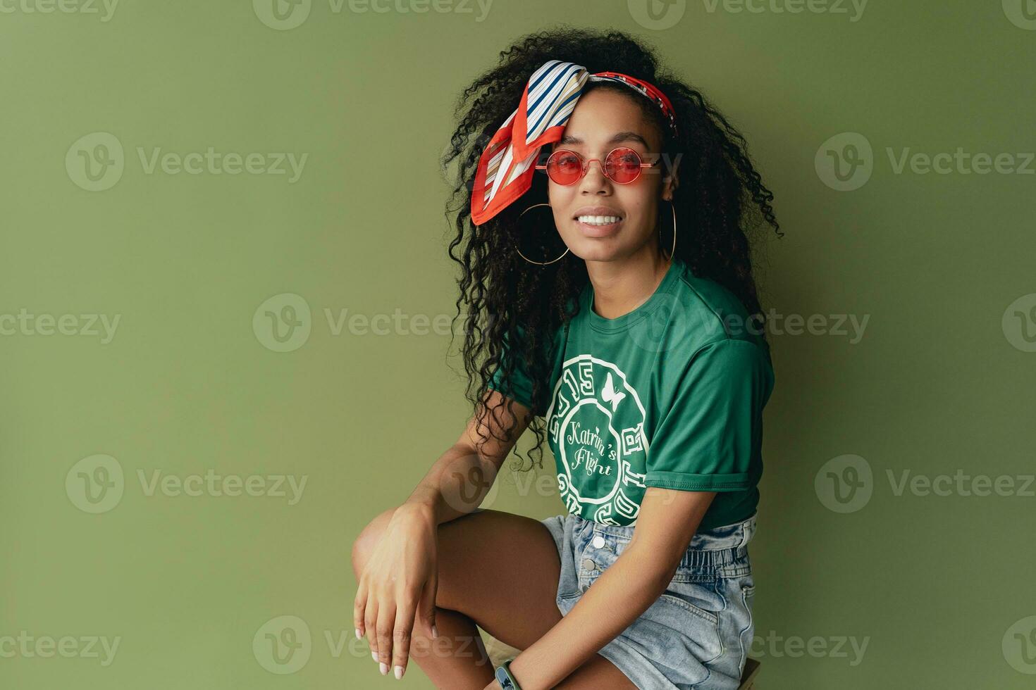 attractive black african american woman posing in stylish hipster outfit on green background photo