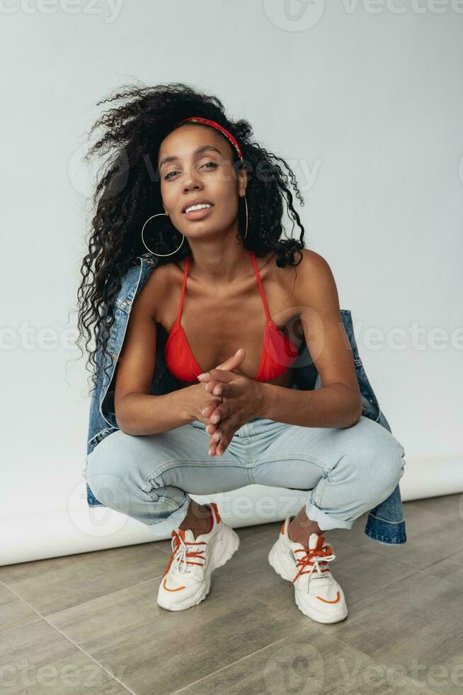 attractive black african american woman posing in stylish hipster outfit on white background photo