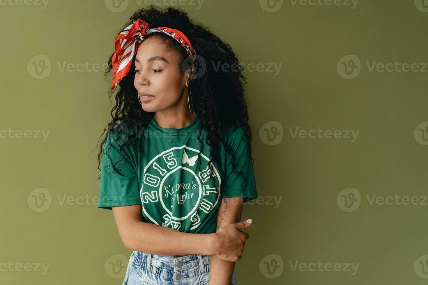 attractive black african american woman posing in stylish hipster outfit on green background photo