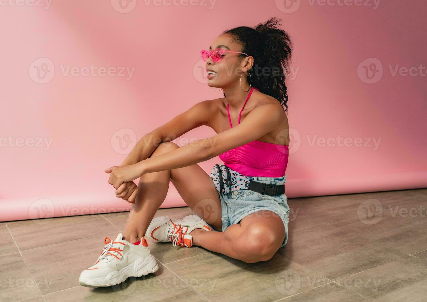 attractive black african american woman in stylish outfit on pink background photo