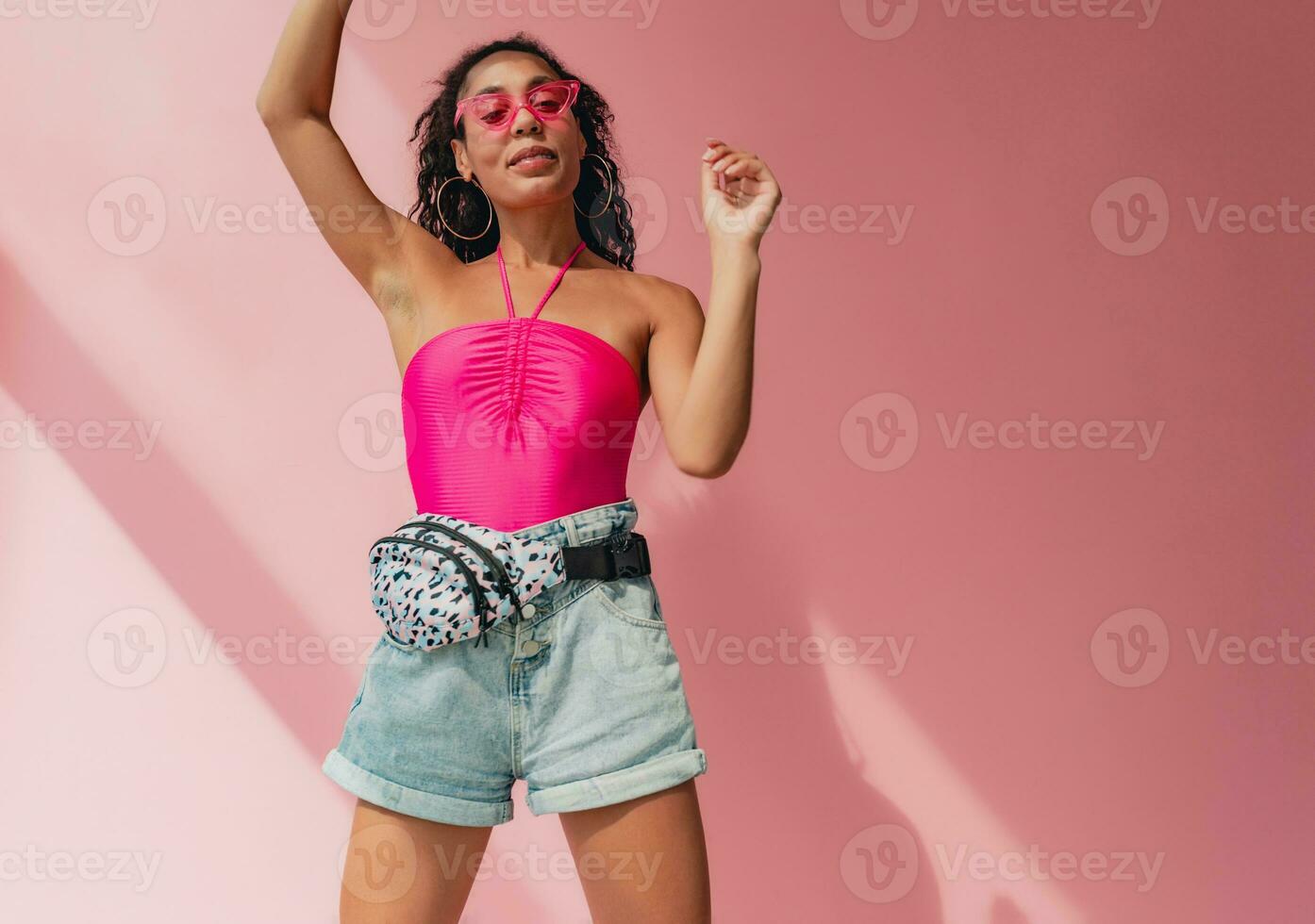 attractive black african american woman in stylish outfit on pink background photo