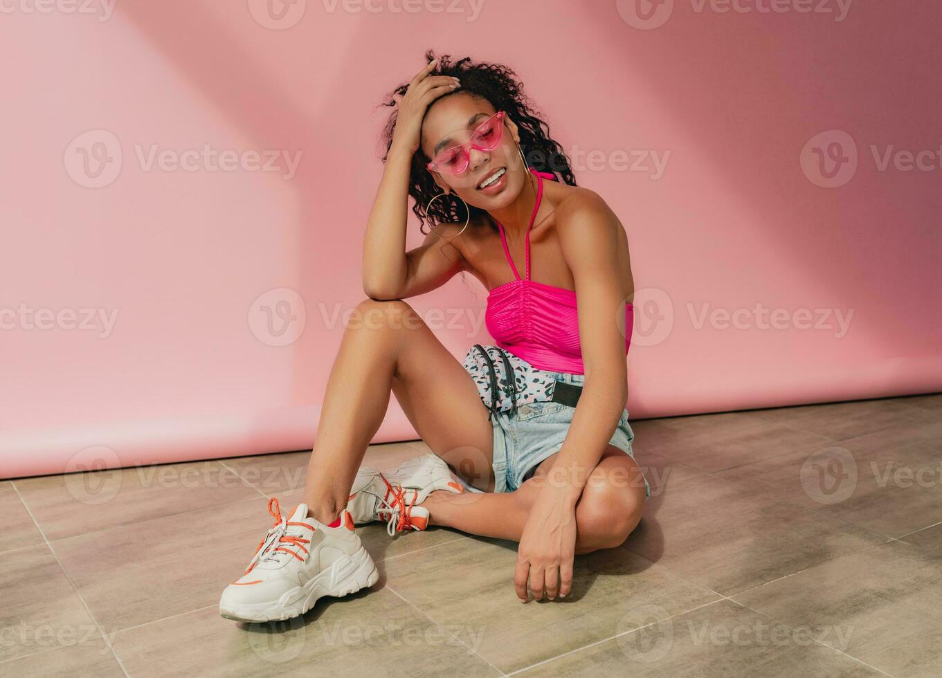 attractive black african american woman in stylish outfit on pink background photo