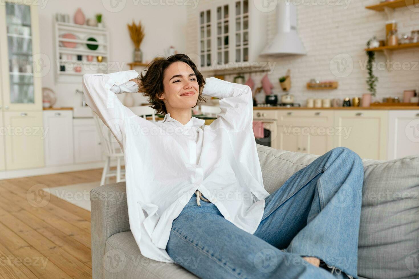 bonito joven mujer relajándose a hogar sentado en sofá, sonriente, feliz, gratis hora foto