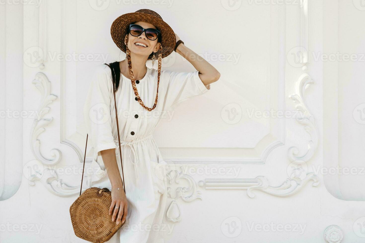 attractive woman walking in city street on vacation dressed in white summer fashion dress photo