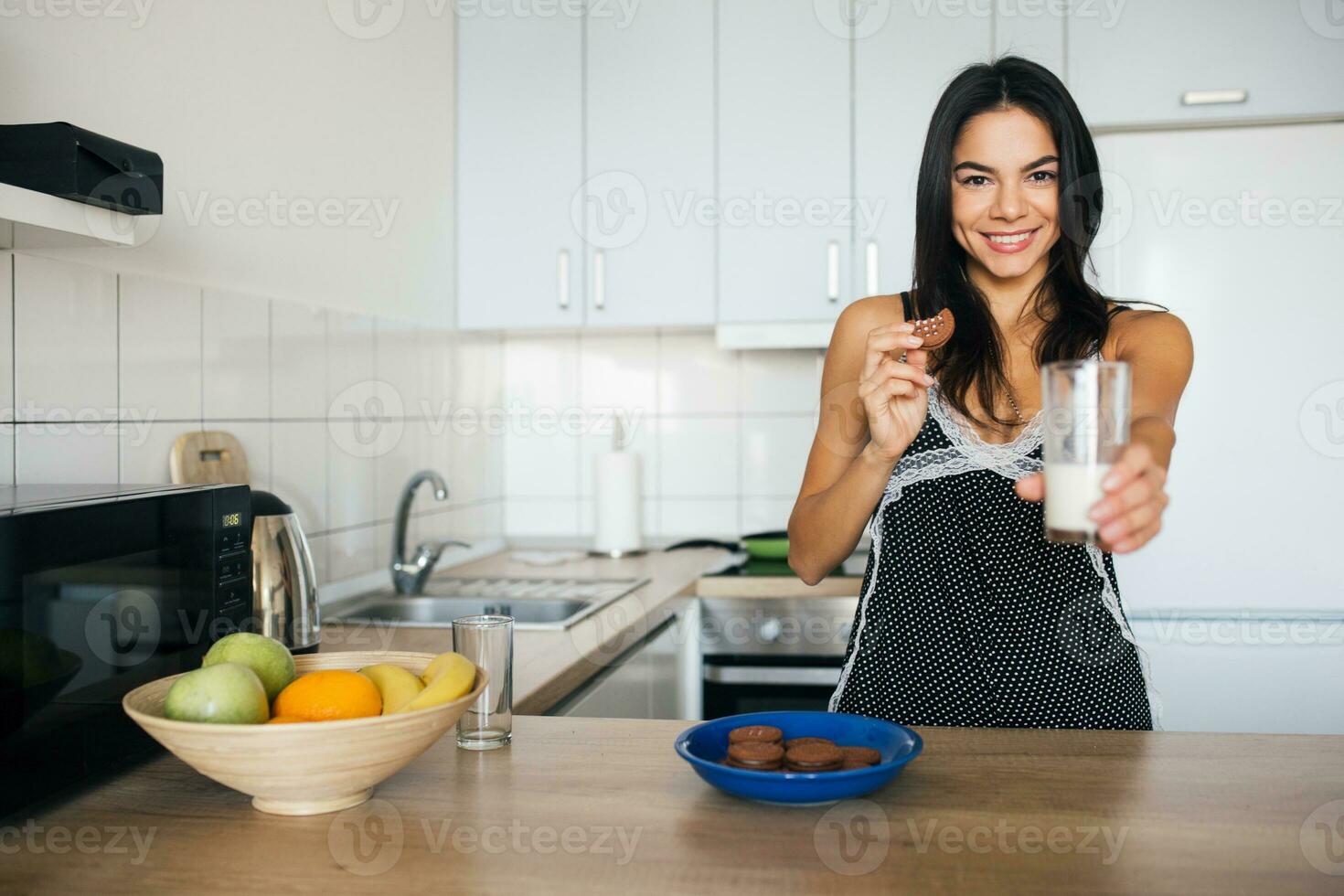 attractive smiling woman in pajamas having breakfast in kitchen photo