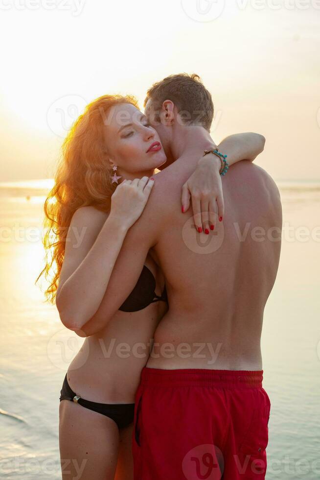 young sexy romantic couple in love happy on summer beach together having fun wearing swim suits photo