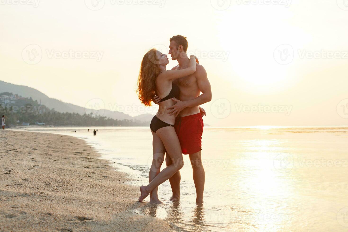 young sexy romantic couple in love happy on summer beach together having fun wearing swim suits photo