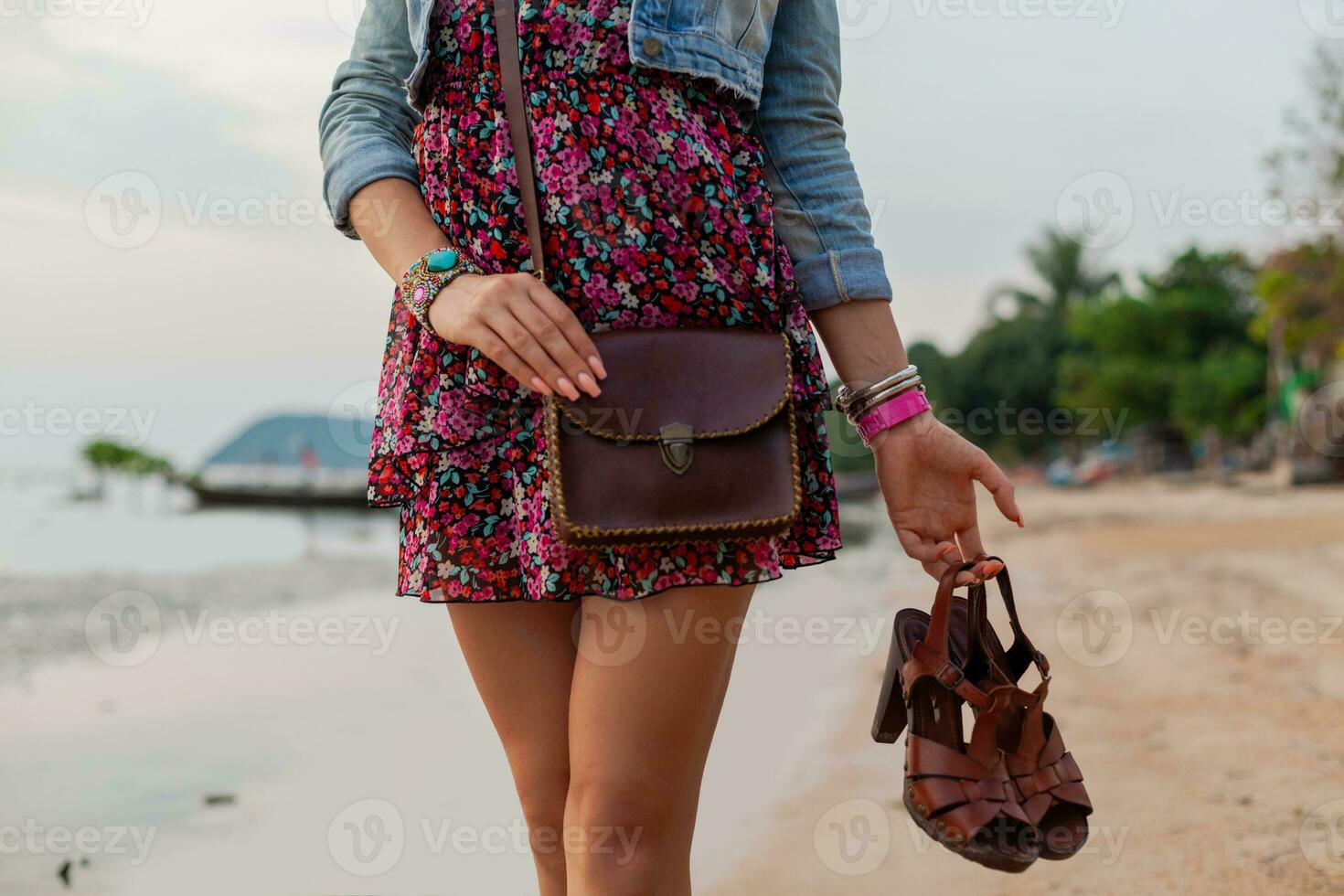 stylish woman in summer dress vacation walking on beach with shoes in hand photo