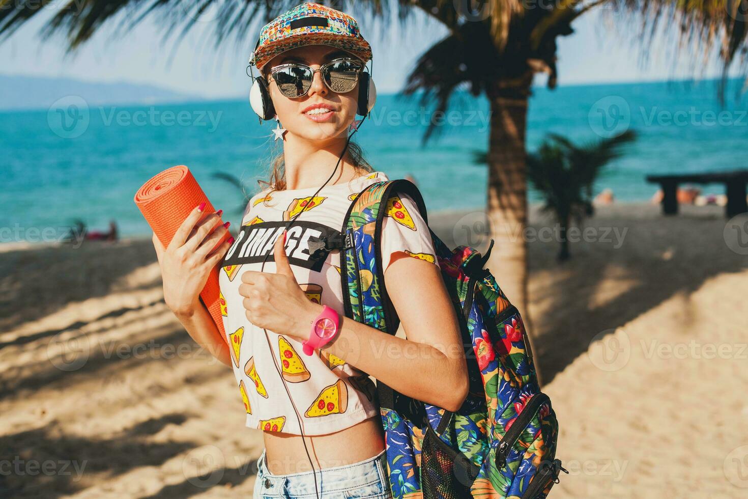 joven hermosa mujer caminando en playa con yoga estera foto