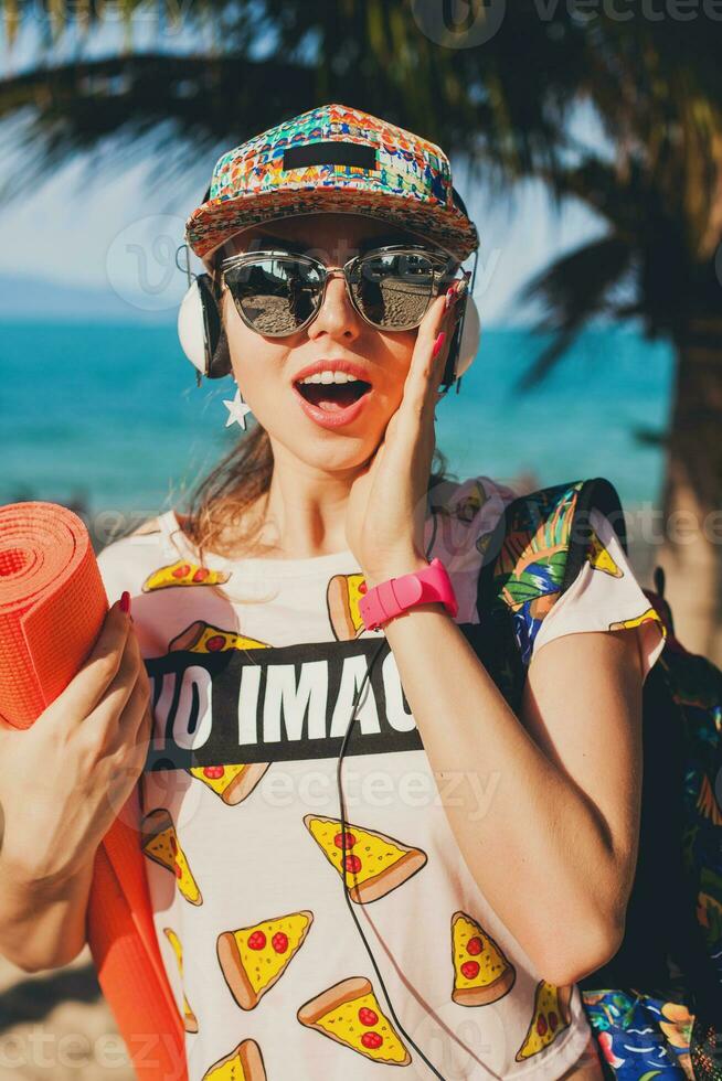 young beautiful woman walking on beach with yoga mat photo