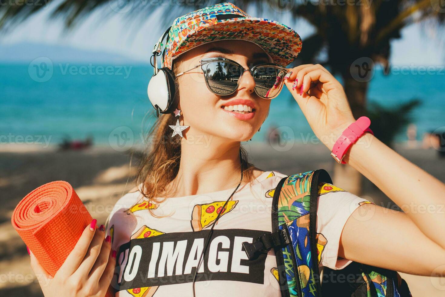 young beautiful woman walking on beach with yoga mat photo