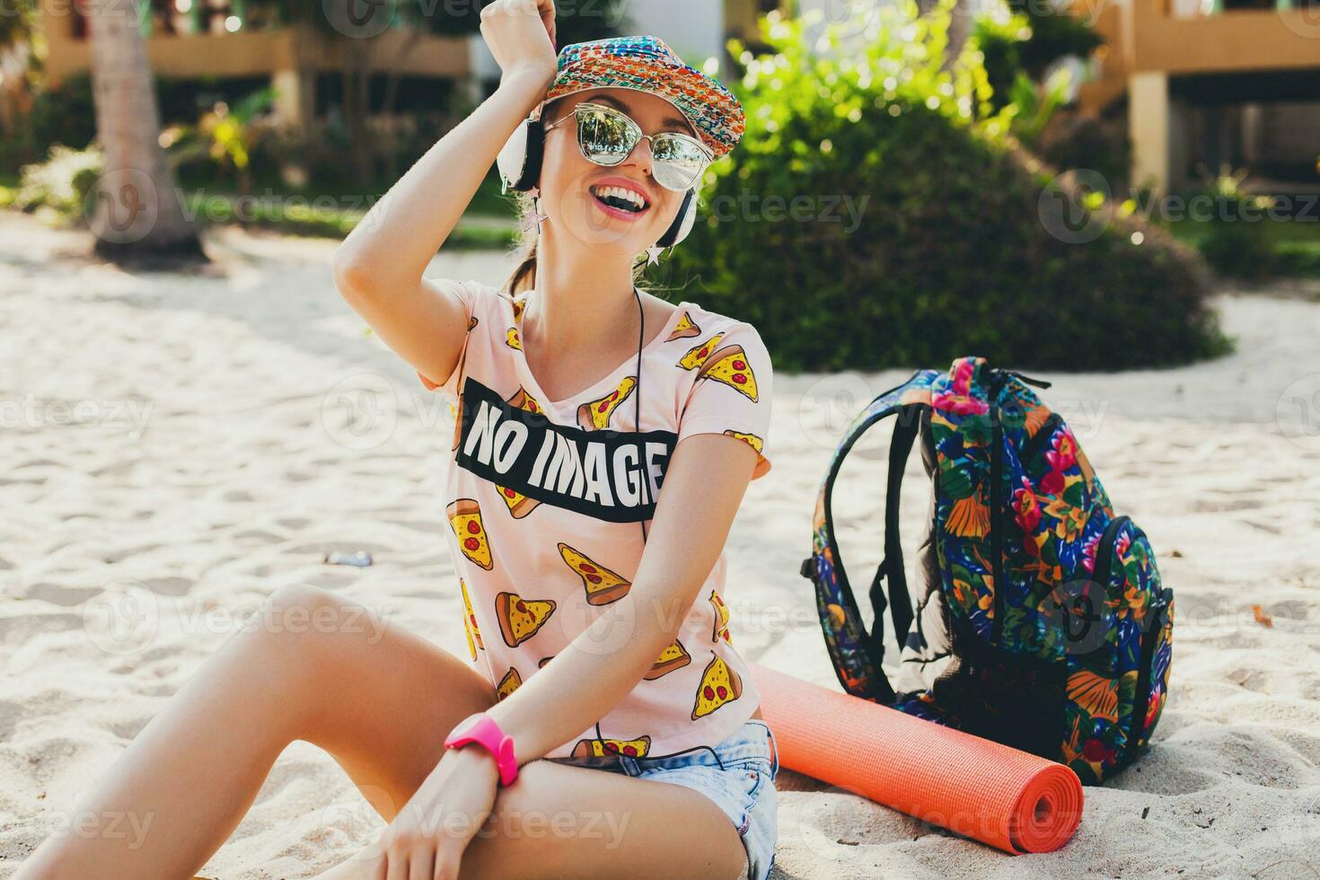 attractive hipster woman sitting on beach listening to music on headphones photo