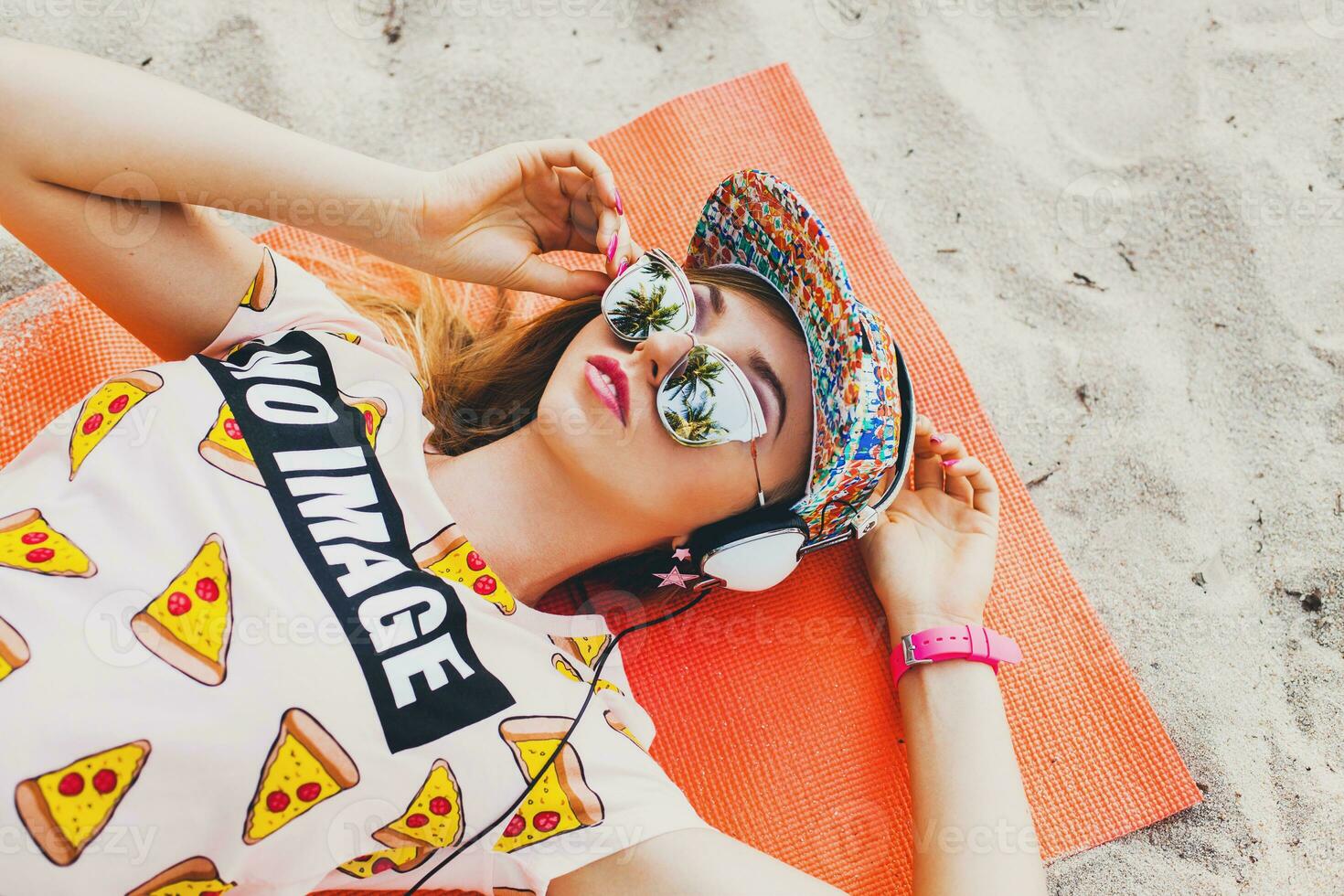 atractivo hipster mujer sentado en playa escuchando a música en auriculares foto