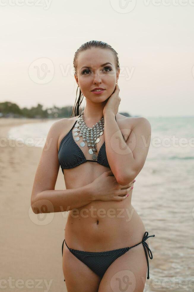 young beautiful blond woman sunbathing on sand beach in bikini swimming suit, vintage necklace photo