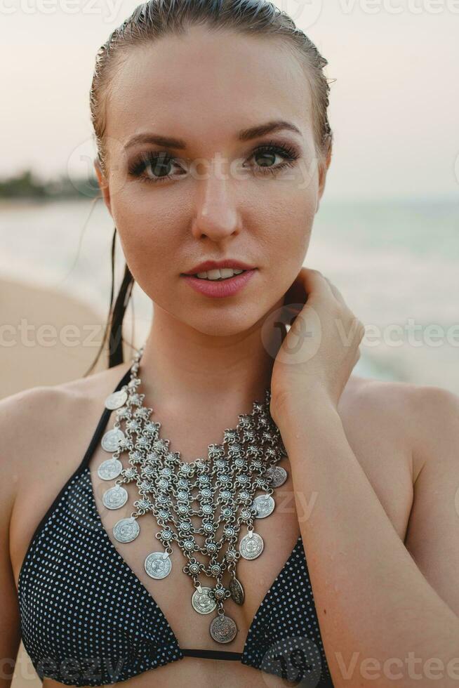 young beautiful blond woman sunbathing on sand beach in bikini swimming suit, vintage necklace photo