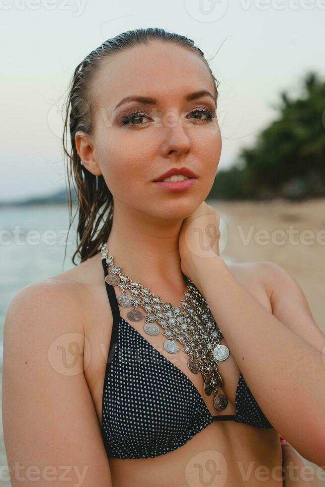 young beautiful blond woman sunbathing on sand beach in bikini swimming suit, vintage necklace photo