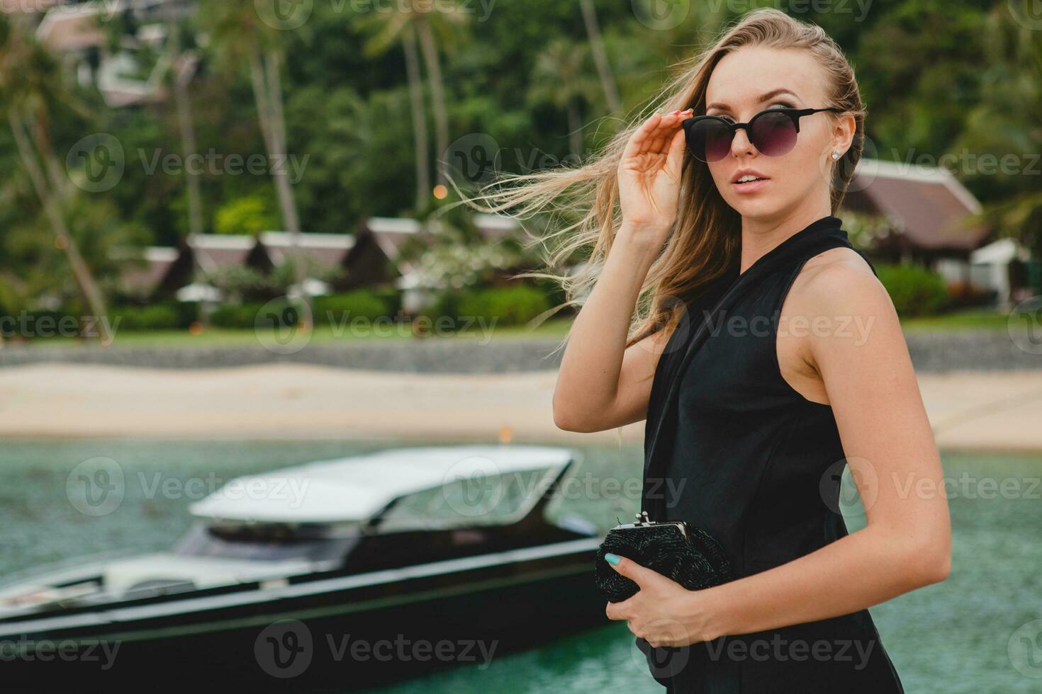 luxury sexy attractive woman dressed in romantic black dress posing on pier in luxury resort hotel photo