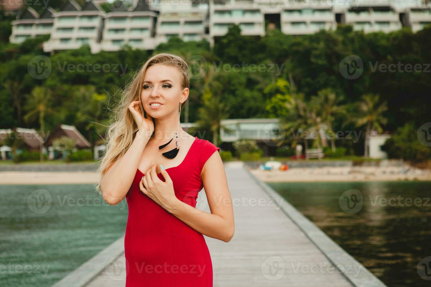 young beautiful attractive woman standing alone on pier red long dress photo