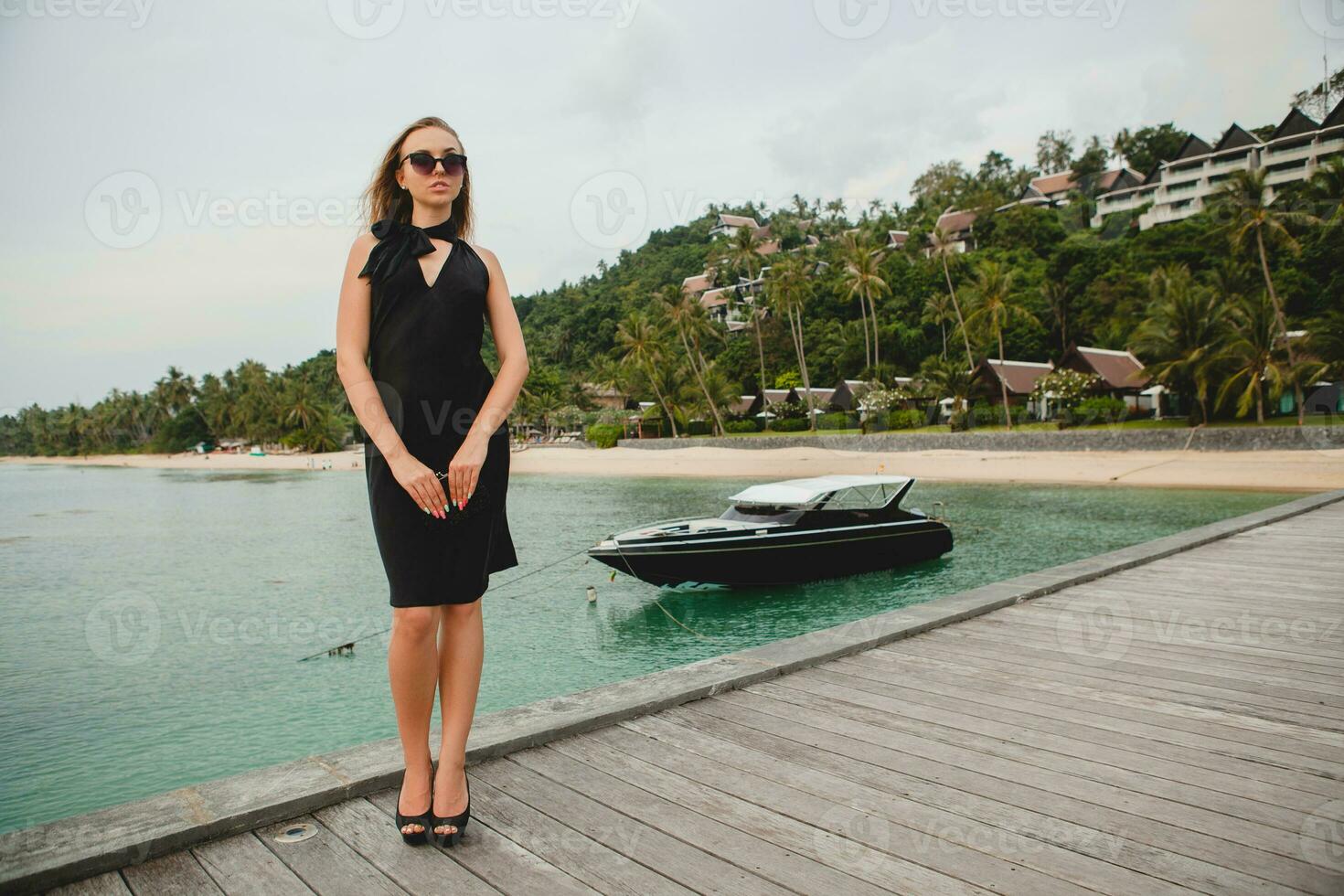 luxury sexy attractive woman dressed in romantic black dress posing on pier in luxury resort hotel photo