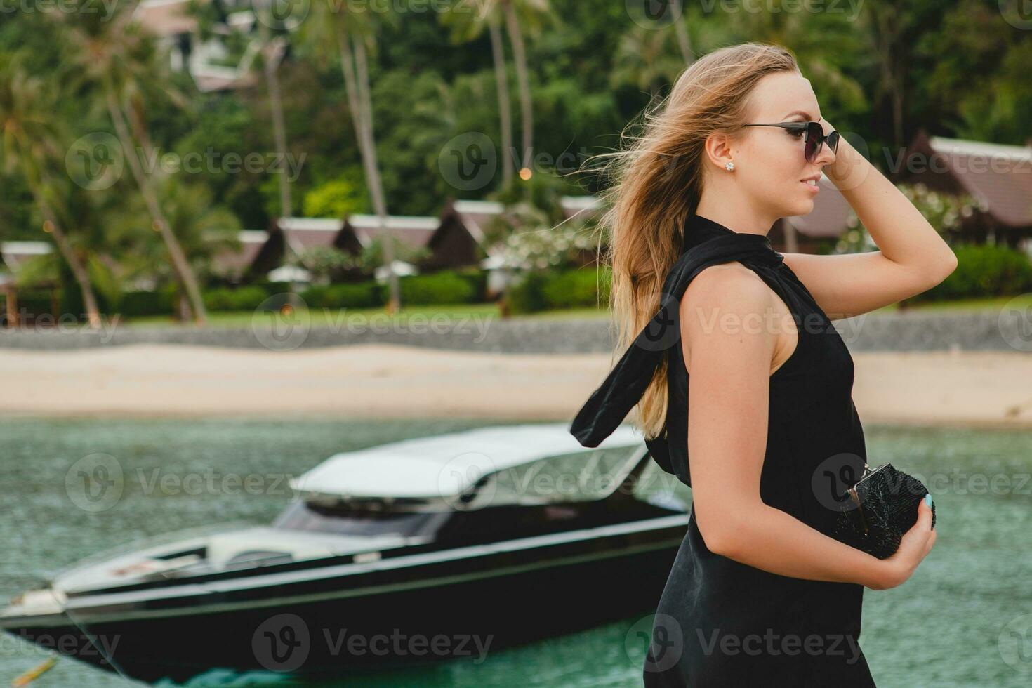 luxury sexy attractive woman dressed in romantic black dress posing on pier in luxury resort hotel photo