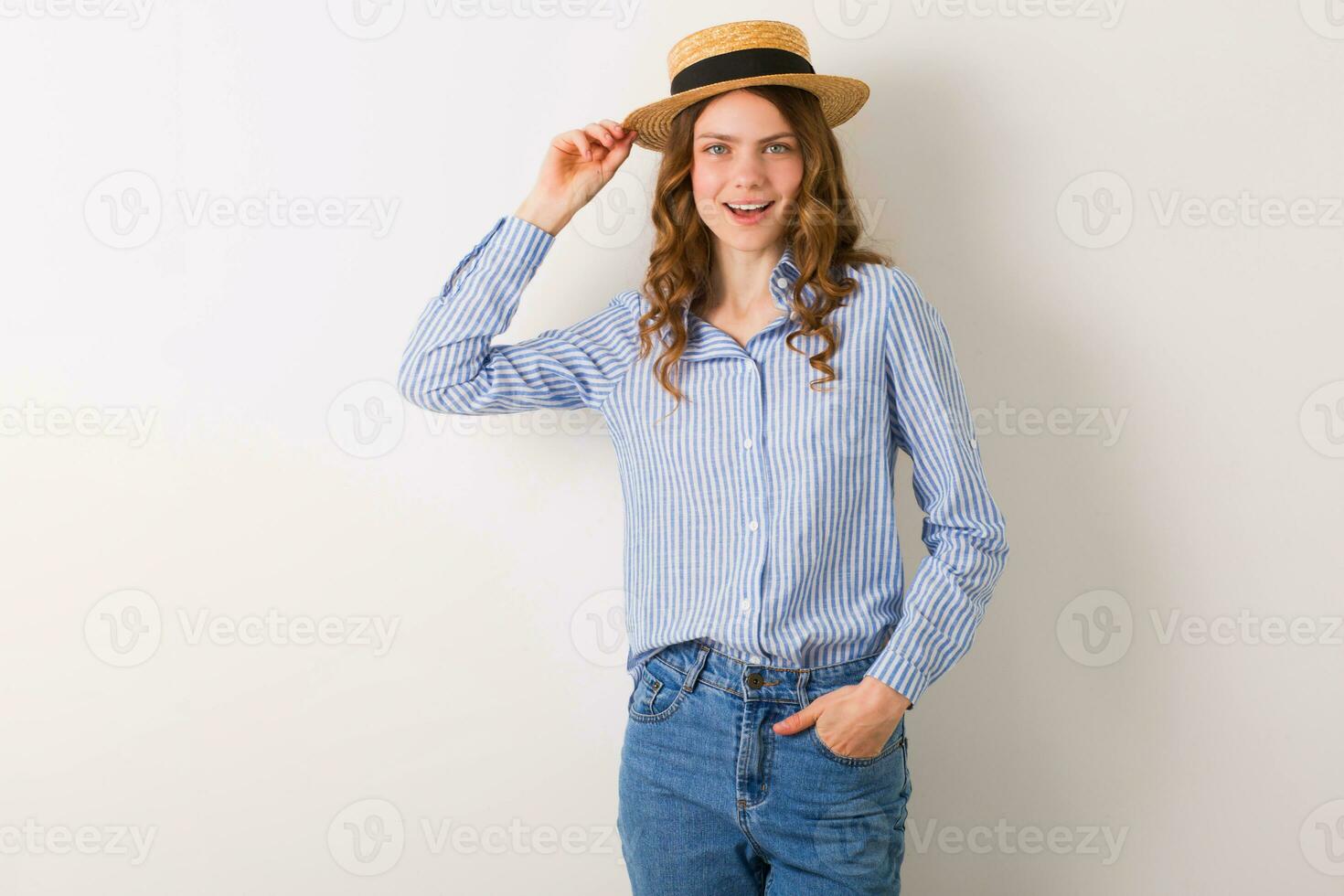 young beautiful stylish woman in summer style outfit posing on white wall wearing straw hat photo