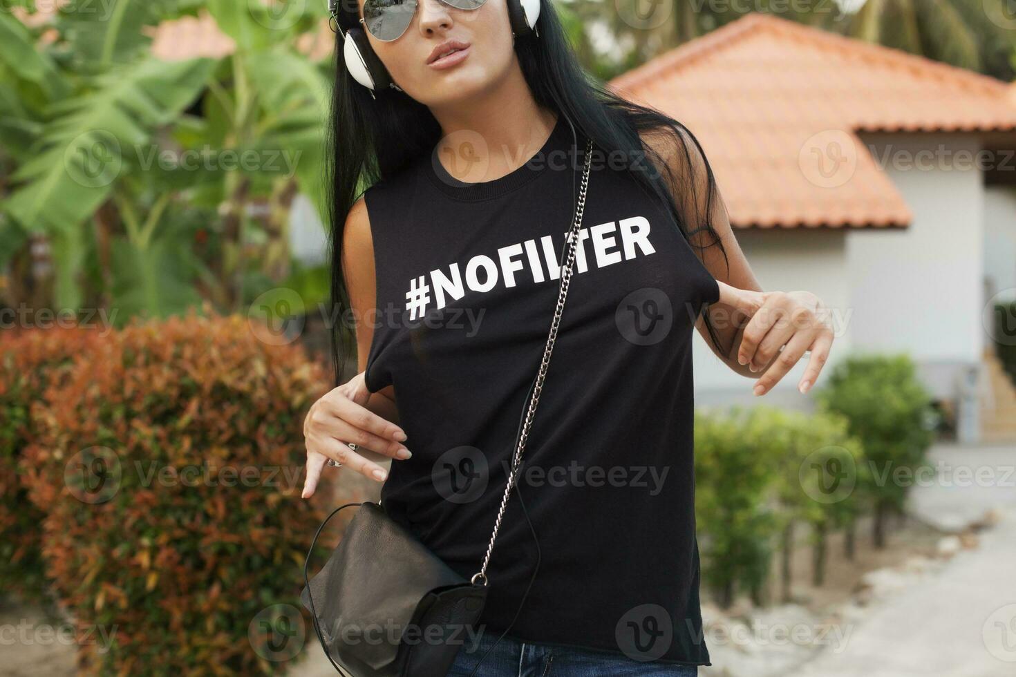 young stylish hipster woman in black t-shirt, jeans, listening to music on headphones photo