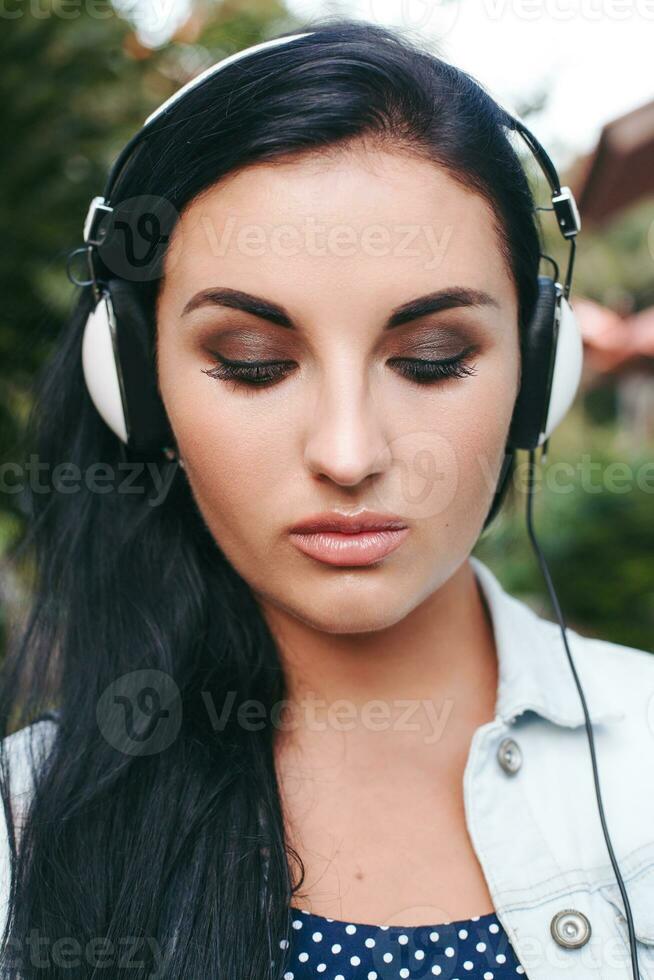 young stylish woman walking, listening to music on headphones photo