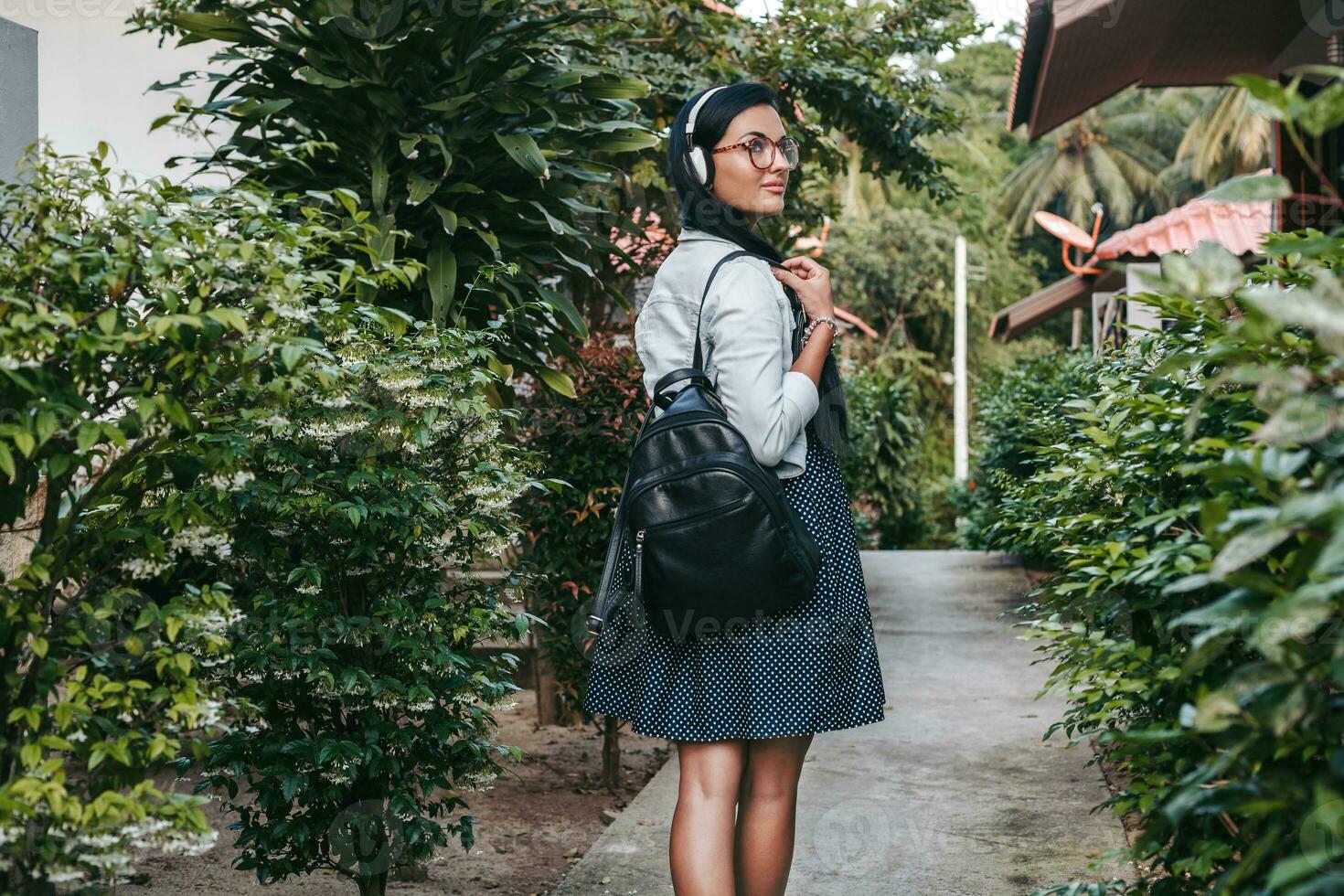 young stylish woman walking, listening to music on headphones photo