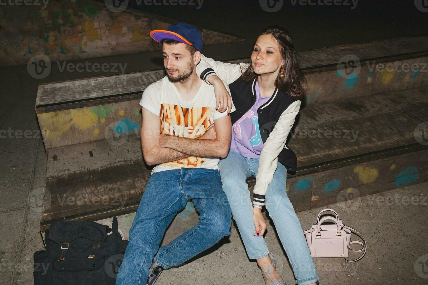 young stylish hipster couple in love, swag outfit, jeans, embrace, cool accessories, sitting happy, having fun photo