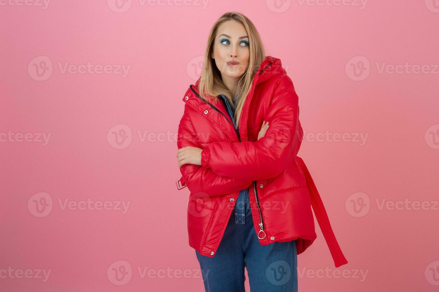 blond happy attractive active woman posing on pink background in colorful winter down jacket of red color, having fun, warm coat fashion trend, smiling photo
