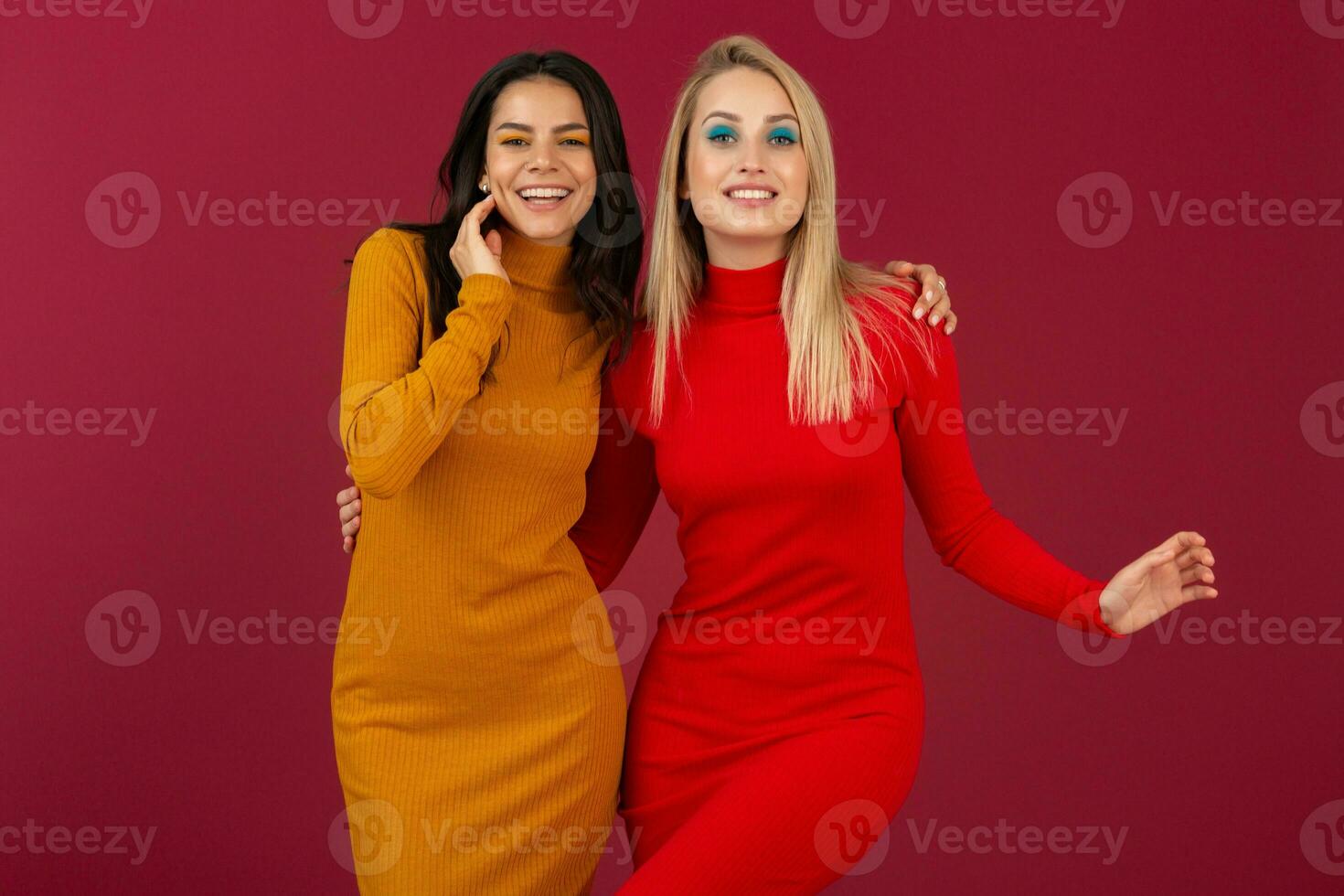 happy smiling pretty stylish women in yellow and red autumn winter fashion knitted dress posing isolated on red studio background photo