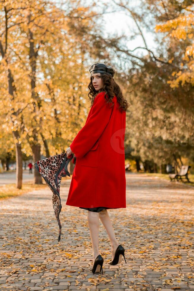 attractive stylish woman walking in park dressed in warm red coat photo