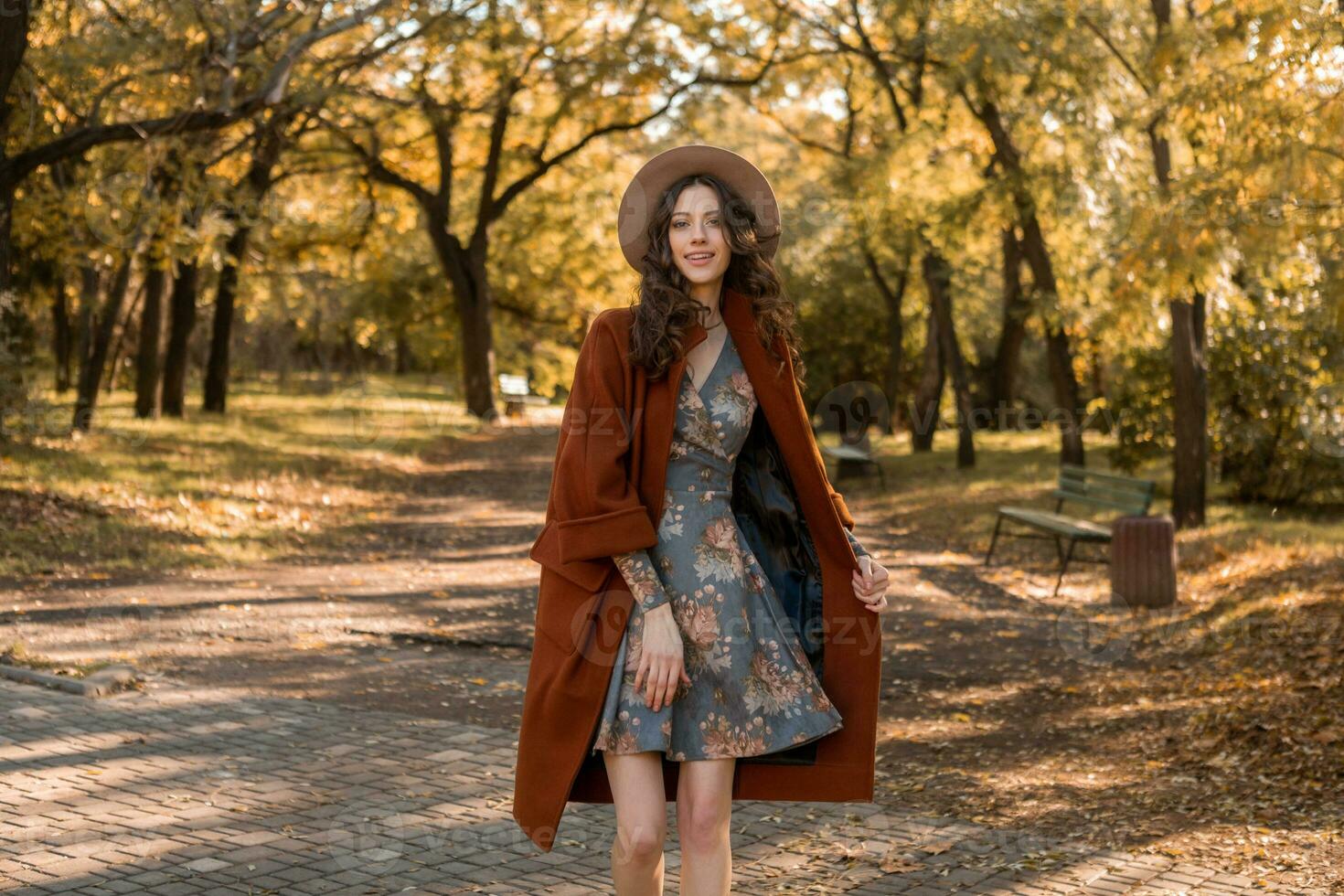 attractive stylish woman walking in park dressed in warm brown coat photo