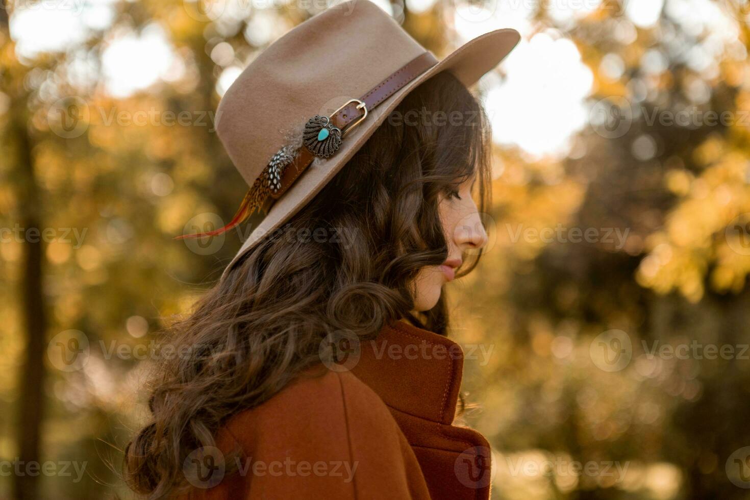 attractive stylish woman walking in park dressed in warm brown coat photo